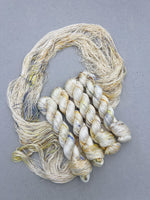 Three skeins of beige and white yarn on a gray background