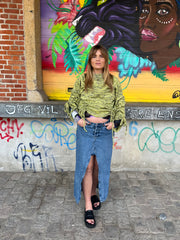 Woman standing in front of a colorful mural with graffiti on a wall.