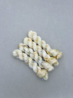 Three skeins of cream-colored yarn on a gray background